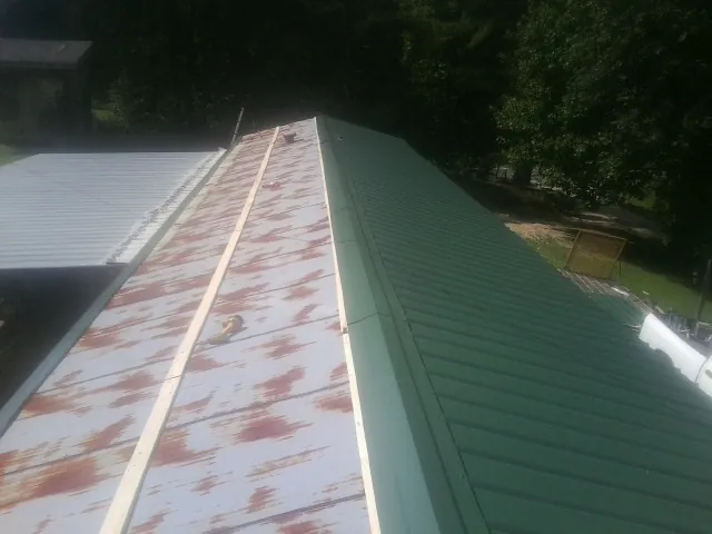 Old rusted panels beside newly installed green metal roofing — Wind Damage Roof Repair by Roofing Brothers in Trail