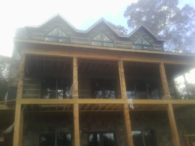 Dormers and porch framing on a large log home under construction — Roof Coating work by our crew in Trail