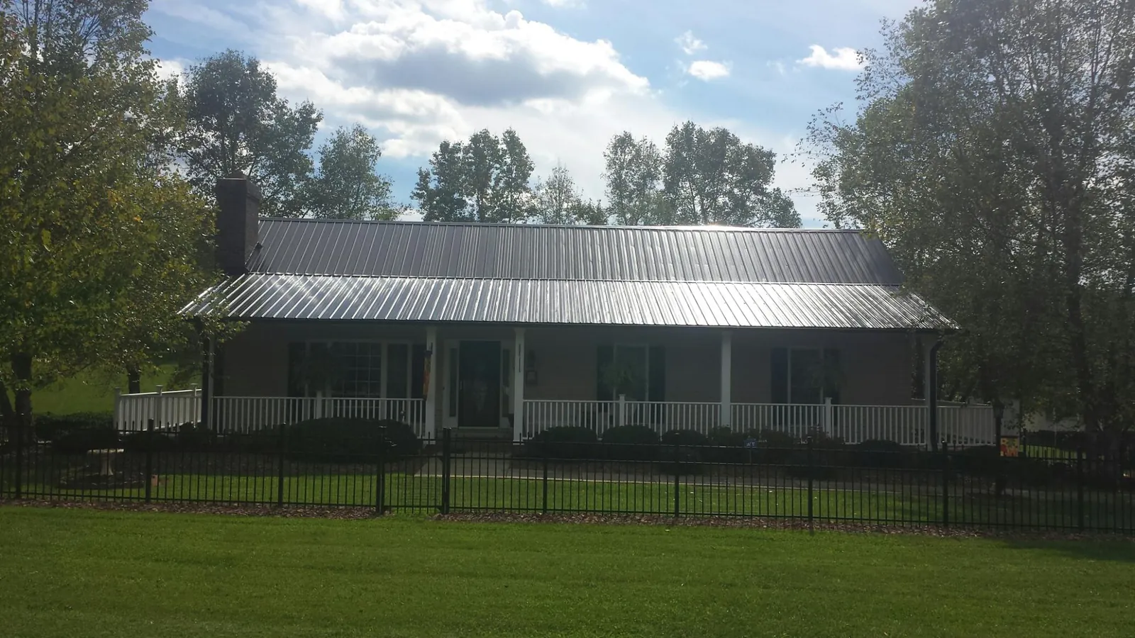 Gray metal roof on a brick ranch with a full width front porch — Gutter Guard Installation work by our crew in Trail