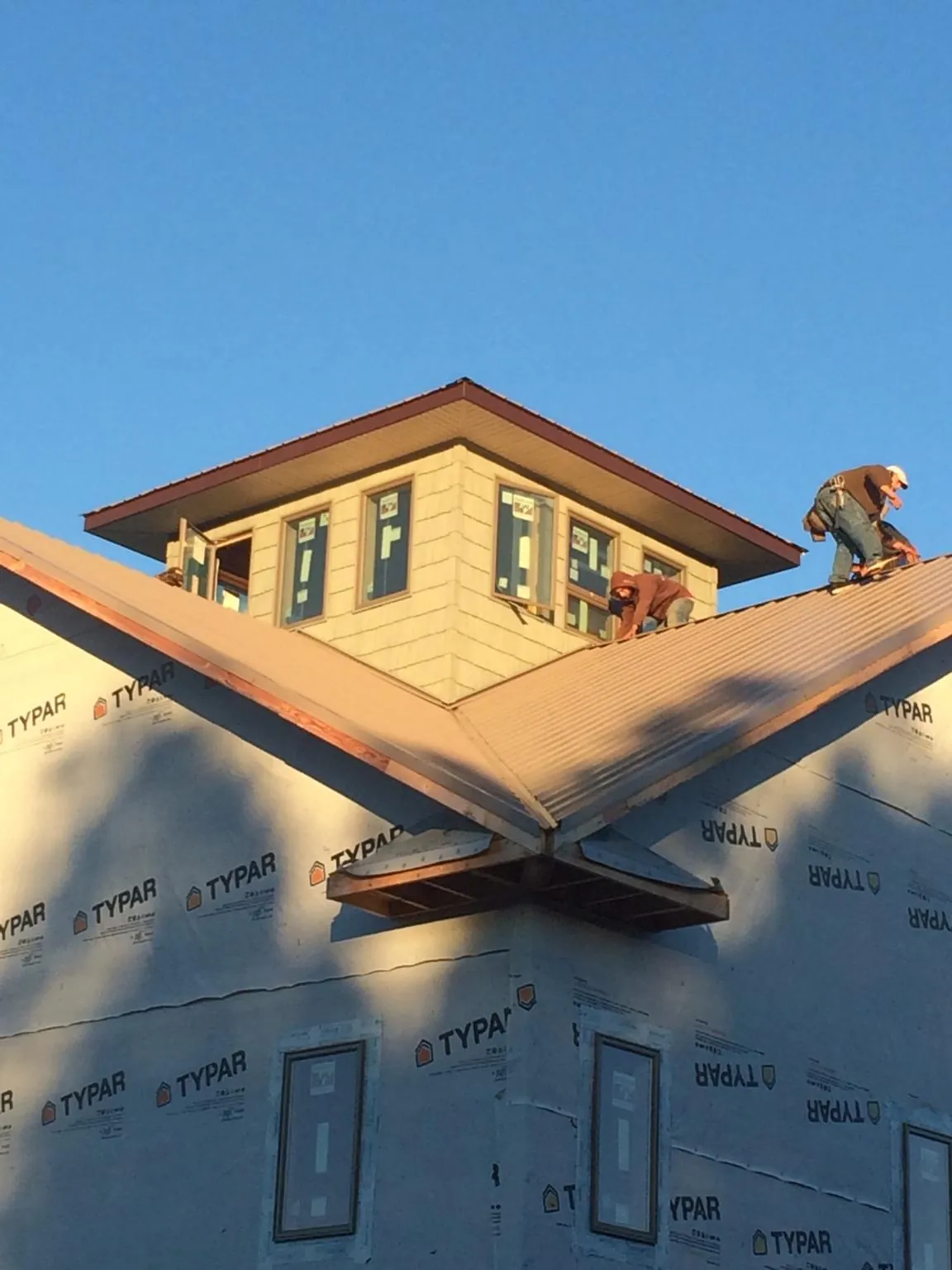 Roofers working around a rooftop cupola on a new metal roof at sunset — Roof Waterproofing in Trail by Roofing Brothers